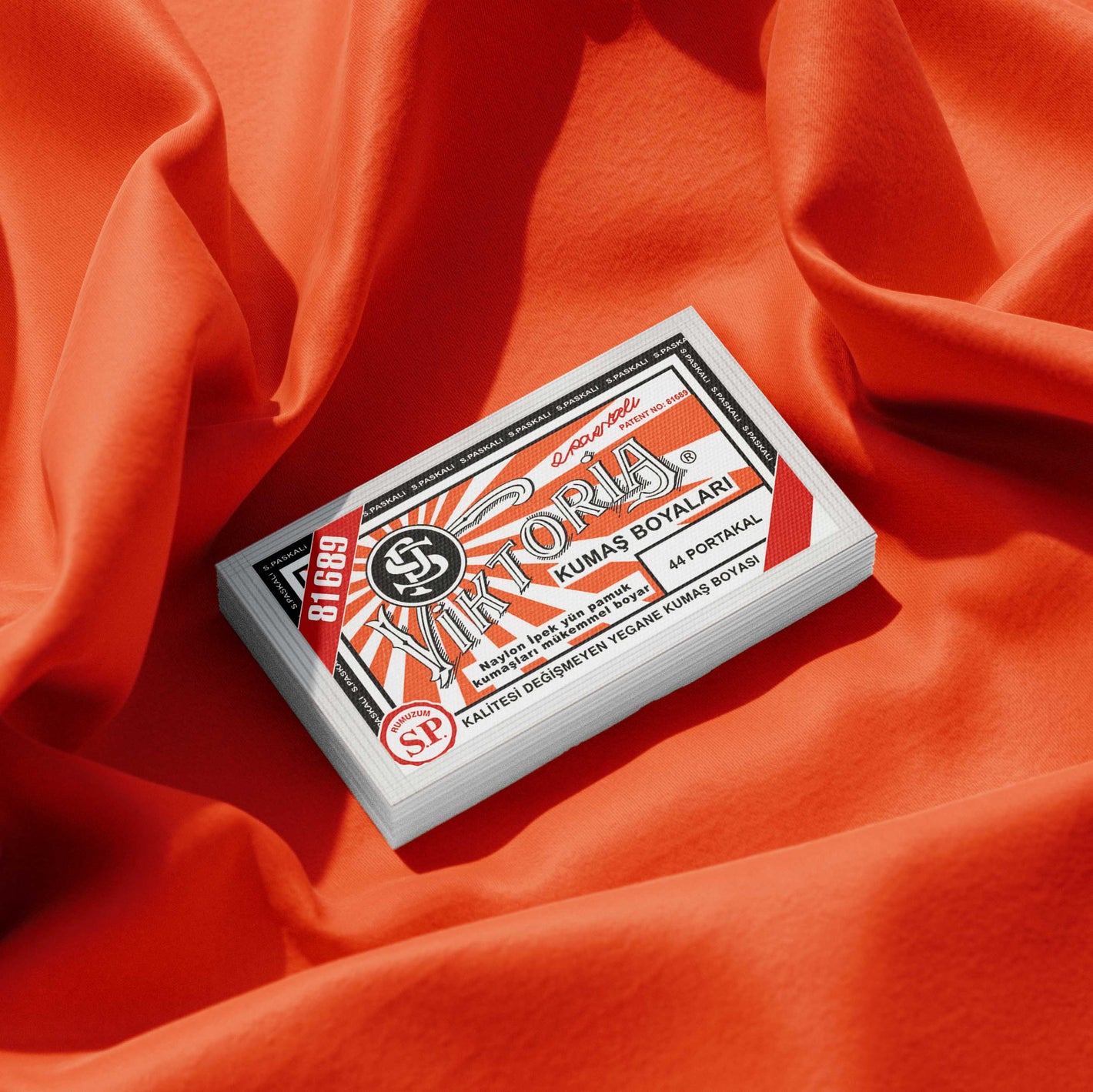 Pack of blood orange fabric dye placed on a vibrant orange fabric background